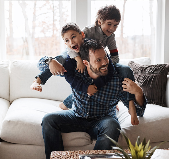 Father wrestling with kids on their couch.