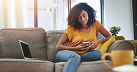 Person sitting on couch using online banking app on their phone.