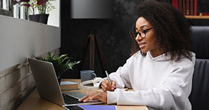 female student wearing glasses working on her laptop computer