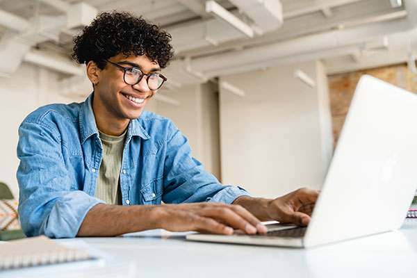 Young person behind laptop learning financial skills.