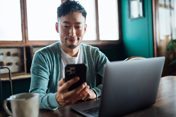 Person using their phone and laptop to bank.